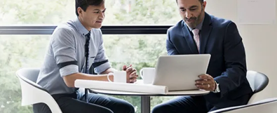 Architects with digital tablet meeting at table in office window.