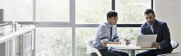 Architects with digital tablet meeting at table in office window