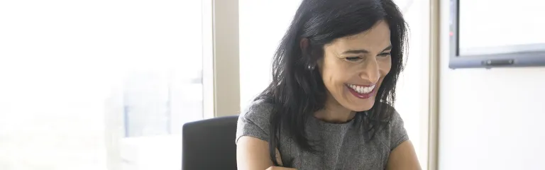 Smiling woman video conferencing at laptop in conference room