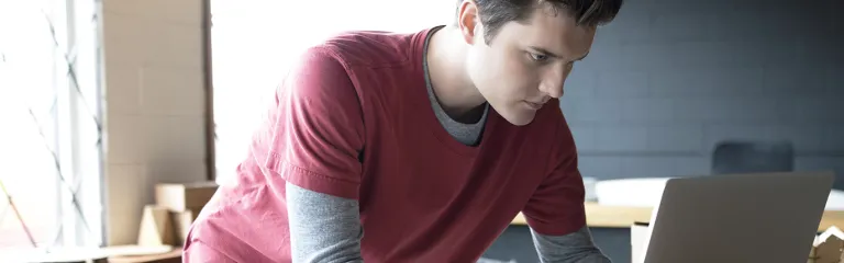 Focused male designer working at laptop in workshop