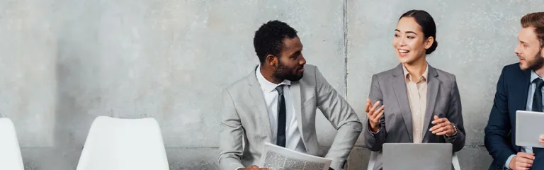  Multi-ethnic business people reading newspaper, using digital devices and talking in waiting hall 