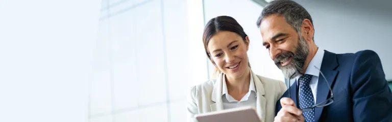Happy business colleagues in modern office talking and using tablet