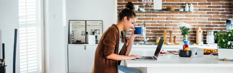 Caucasian woman using laptop in kitchen.