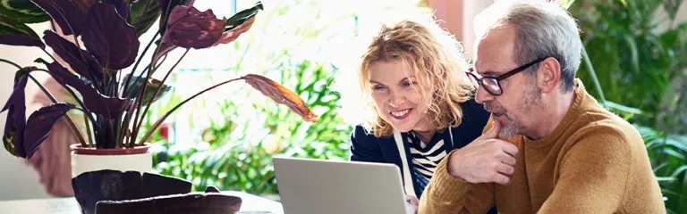 Mature couple in their 50s using computer at home.
