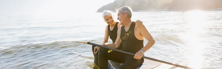 Senior couple on paddle board in ocean.
