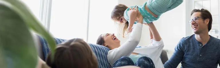 Happy mother with young daughter and father at home