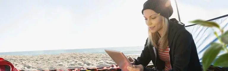 Woman using digital tablet in tent on beach