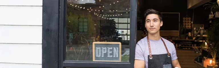 Male shop owner standing in doorway looking away in anticipation