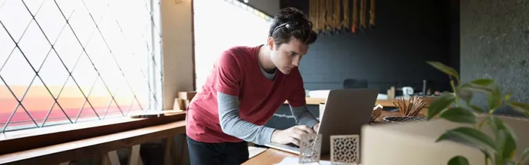 Focused male designer working at laptop in workshop